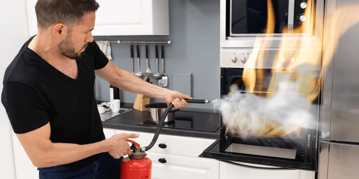 Man putting out a kitchen fire with an extinguisher